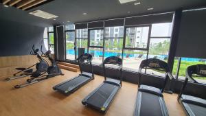a gym with treadmills and ellipticals in a room with windows at Gamuda Cove Homestay in Banting