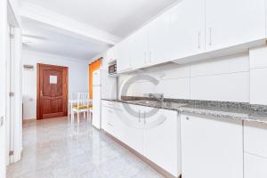 Una cocina blanca con gabinetes blancos y una mesa. en San Agustin Ocean View, en Maspalomas