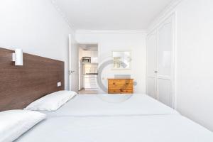 Dormitorio blanco con cama blanca y cabecero de madera en San Agustin Ocean View, en Maspalomas 9 fotos más