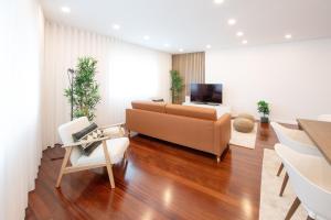 a living room with a couch and a tv at Costa Nova Premium Apartment & Pool in Costa Nova