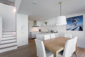 a kitchen and dining room with a wooden table and white chairs at 4-bed Luxury Villa 5-star Resort in Caldes de Malavella