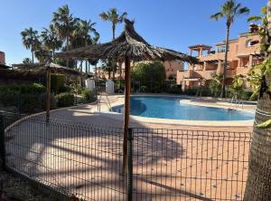 a fence with an umbrella next to a swimming pool at Vera playa in Vera