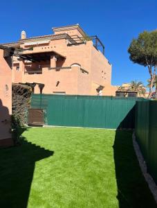 a house with a green fence and a green yard at Vera playa in Vera +2 photos