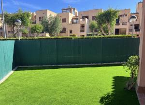 a fence with green grass in front of a building at Vera playa in Vera