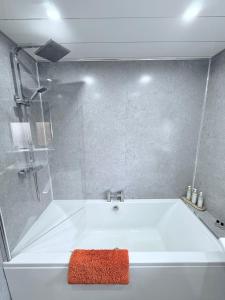 a white bath tub with a red towel on it at Ochil View Holiday Let in Tullibody +12 photos