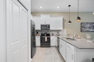 a kitchen with white cabinets and a black refrigerator at CONDO 2bed2bath next to Disney w Free Water Park in Kissimmee