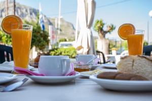 a table with plates of food and two glasses of orange juice at Vasilios Marinos Rooms in Korinthos