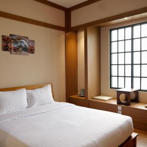 a bedroom with a white bed and a window at The Ryokan Semarang in Semarang