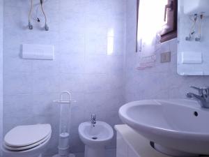 a white bathroom with a toilet and a sink at Residenza Piras - Budoni Sweet Home in Tanaunella