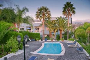 une piscine avec des palmiers et un bâtiment dans l'établissement Acogedor Apartamento con Piscina y Jardin, à Los Llanos de Aridane