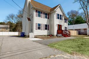 a white house with a red door on a street at Buttermilk Bliss in Wareham