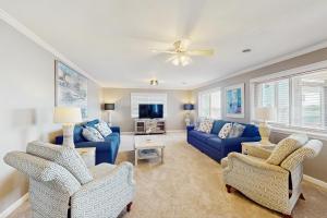 sala de estar con sofás azules y ventilador de techo en Waterfront Oasis, en Carolina Beach