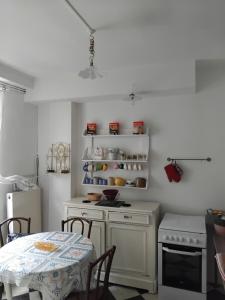 a white kitchen with a table and a white refrigerator at La Tour Des Douves in La Celle-sous-Gouzon