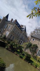 a large building next to a body of water at La Tour Des Douves in La Celle-sous-Gouzon