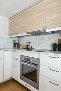 a kitchen with white cabinets and a stainless steel oven at Apartment near city centre, free parking in Lillehammer