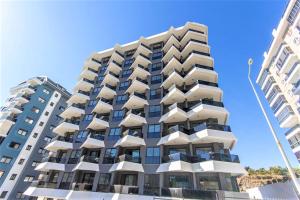 an apartment building with balconies on the beach at 0017 White Sail Cozy 1-Bedroom Apartment Steps from Yekta Mall in Mahmutlar, Alanya in Alanya
