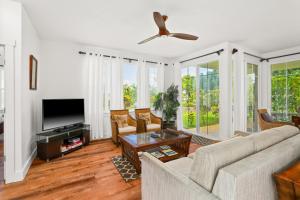 a living room with a couch and a tv at Tropical Princeville Condo with Private Lanai in Princeville