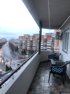 a balcony with chairs and a view of a city at Alfredo Apartament in Buzau