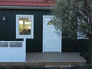 a black house with a white door and a wooden porch at Villa Svanviken in Svedala