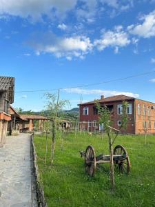an old wagon sitting in the grass next to a building at Villa Obcha - Whispering Vines Guesthouse in Bagdatʼi