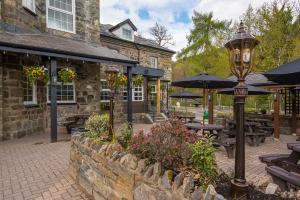 a street light in front of a restaurant with tables and umbrellas at The Swallow Falls Inn - The Inn Collection Group in Betws-y-coed