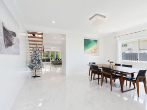 un comedor con mesa y sillas y un árbol de Navidad en Thorneside seaside dream home near the blue sea, en Birkdale