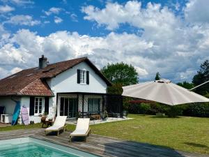 a house with a pool and an umbrella at Sukha surf lodge in Lit-et-Mixe