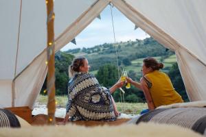 two women are sitting in a tent with drinks at Unwind Camping in Evercreech