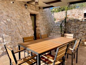 a wooden table and chairs in front of a stone wall at TRULLO VISTA MARE - Mini piscina riscaldata con idromassaggio in Marina San Gregorio