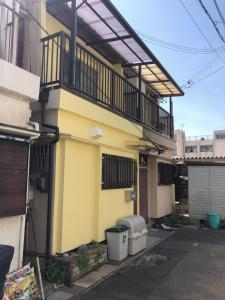 a yellow building with a balcony and two trash cans at HOKUSAI-KAN Osaka Taisho in Osaka