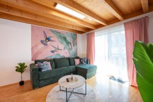 a living room with a green couch and a table at NAMASTÉ Homes - Ferienwohnung mit Balkon & Carport in Bad Windsheim