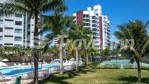 a resort with a pool and palm trees and buildings at Travel Inn Flats Riviera in Riviera de São Lourenço