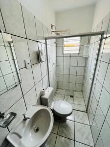 a white bathroom with a toilet and a sink at Polis Hotel in Pindamonhangaba