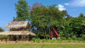 a small house with a straw roof and a hut at VR Nature Cottage CABANA in Wellawaya