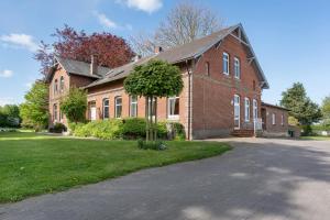 a large brick building with a tree in front of it at Ferienwohnung 'am Park' in Rabenkirchen-Faulück