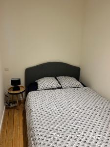 a bedroom with a bed with a black headboard and a table at Studio au centre ville de Dole in Dole