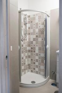 une douche dans une salle de bain avec une porte vitrée dans l'établissement Magia home, à Caserte