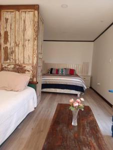 1 dormitorio con 2 camas y un jarrón de flores sobre una mesa en Espacio modular privado, en Coquimbo