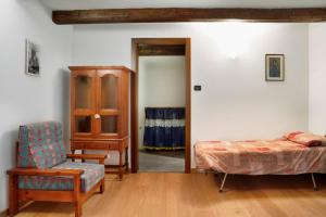 a bedroom with a bed and a chair and a cabinet at Chalet Provenzale Trilocale in Acceglio