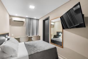 a hotel room with a bed and a flat screen tv at Pousada Recife in Recife