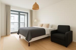 a bedroom with a bed and a chair at City Home Finland Big Luxury Suite - Spacious Suite with Own SAUNA, One Bedroom and Furnished Balcony next to Train Station in Tampere +2 photos