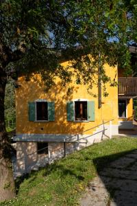a yellow building with two windows and a tree at Borgo Segreto del Garda in Monzambano