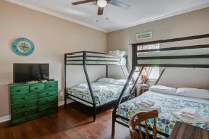 a bedroom with two bunk beds and a television at Happy Place by Bolivar Escapes in Crystal Beach
