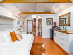 a bedroom with a white bed and a kitchen at Star Studio, A Garden Retreat near University of Oregon in Eugene