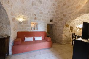 ein Wohnzimmer mit einem roten Sofa in einer Steinwand in der Unterkunft Esclusiva tenuta salentina by Pugliadamare in San Michele Salentino + 70 Fotos