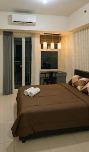 a bedroom with a bed with two towels on it at LuxBedAndersonPakuwon by BnB in Surabaya