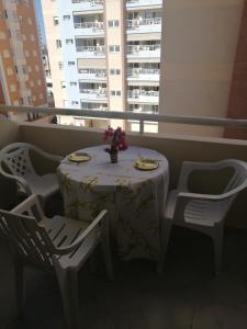 einen Tisch und Stühle mit einem Tisch und Blumen auf dem Balkon in der Unterkunft Bonita piscina y playa de gandia in Puerto de Gandía