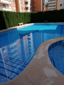 einem blauen Pool mit Spiegelung eines Gebäudes in der Unterkunft Bonita piscina y playa de gandia in Puerto de Gandía