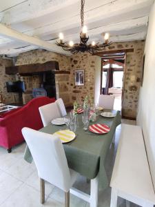 ein Esszimmer mit einem grünen Tisch und weißen Stühlen in der Unterkunft Maison en pierre avec piscine in Billac