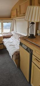 a bed in an rv with a lamp on a desk at Caravan in Leicester